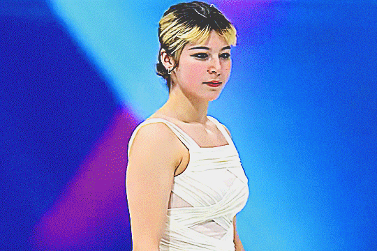 half body shot of alysa liu gliding around the ice before she starts her individual short program at the 2026 milan olympics, with a gentle smile on her face