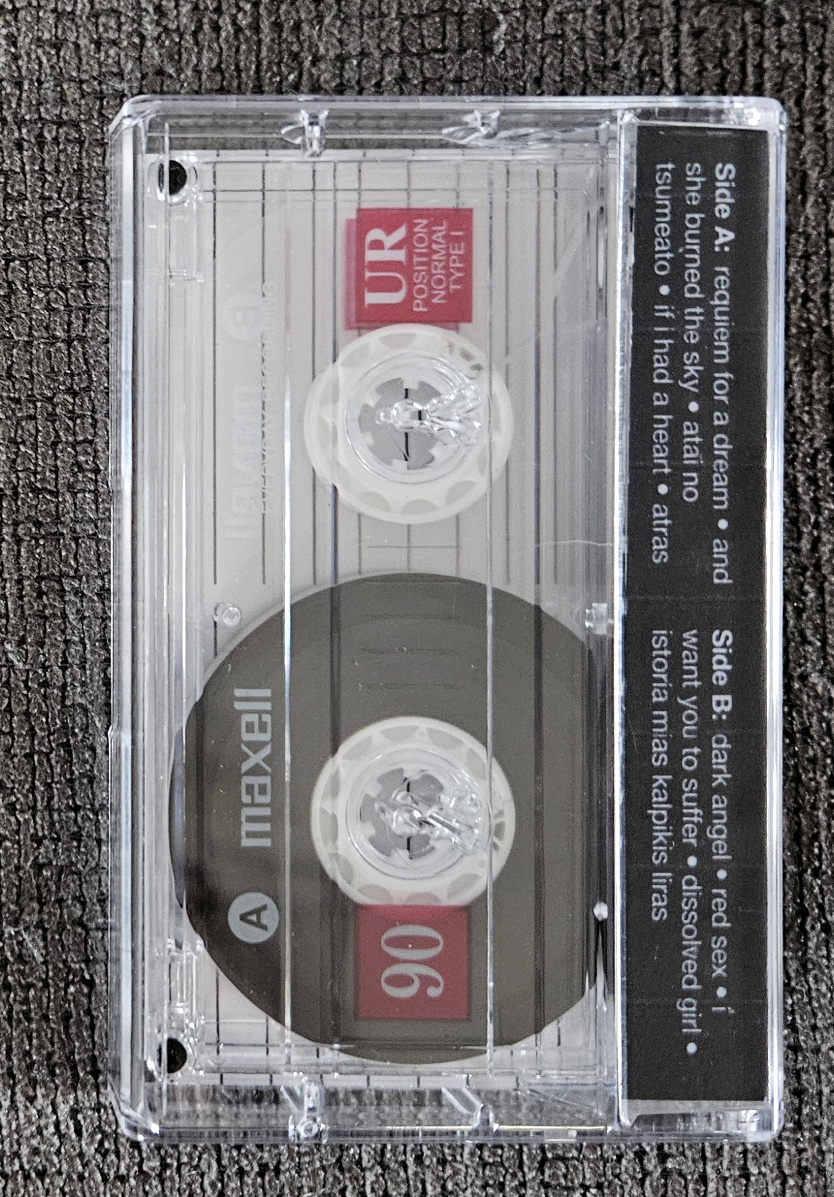 my physical recorded tape for the above playlist in a case with a custom j-card, but taken from the back of the case, and the case is clear so the cassette tape inside is visible
