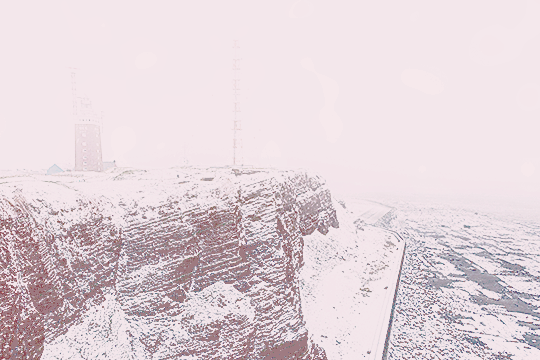original photo by Thomas Haeusler of a snow-covered winter mountain landscape, with lots of fog and buildings in the distance. the photo is sharpened and tinted pink