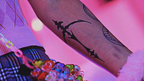 two shots from the ARTMS virtual angel video, one of a girl's arm with a bow and arrow tattoo, the other with the girl's face, specifically the side of her face zoomed in on her eye, as she looks down