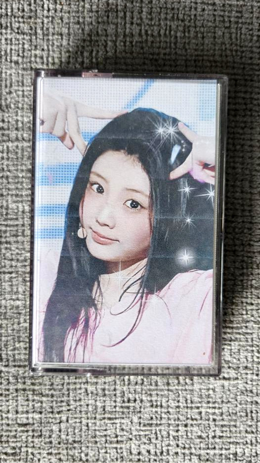 my physical recorded tape for the below playlist in a case with a custom j-card showing the cover art, which is an edit of wonhee from the k-pop group i'll it doing an ending fairy pose on stage with sparkles edited over it