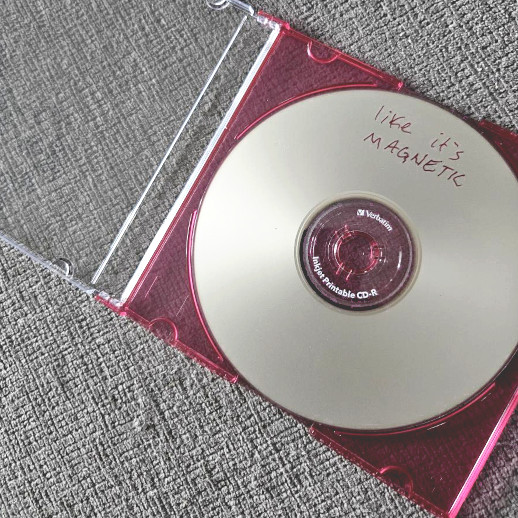 my physical burned CD for this mix in a jewel case, which is open to show the disc inside that has text written in red marker ink that reads 'like it's magnetic'