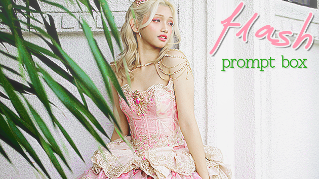 k-pop idol gehlee, member of group UNIS, dressed as a princess and posing against a wall with some green foliage in front of her. there is text to the side that says 'flash prompt box', the first word in pink cursive and the latter two in green serif font