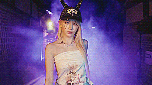 LE SSERAFIM miyawaki sakura in a purple lit smokey area walking in a cool style forward and tilting her head back